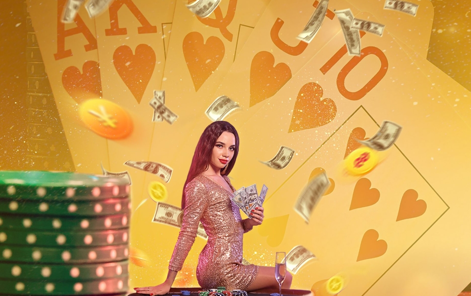 Model in golden dress holding some cash, posing sitting sideways on stack of colorful chips with glass of champagne. Background with playing cards, flying money and backlight. Poker, casino. Close up